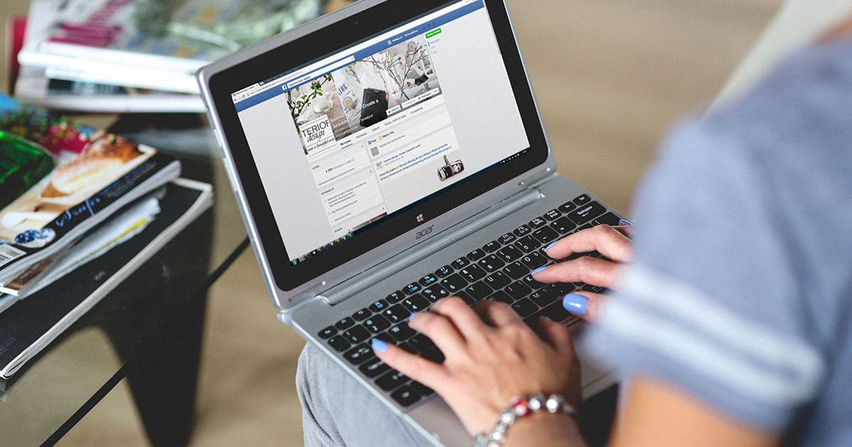 A photo of a woman accessing Facebook on a laptop